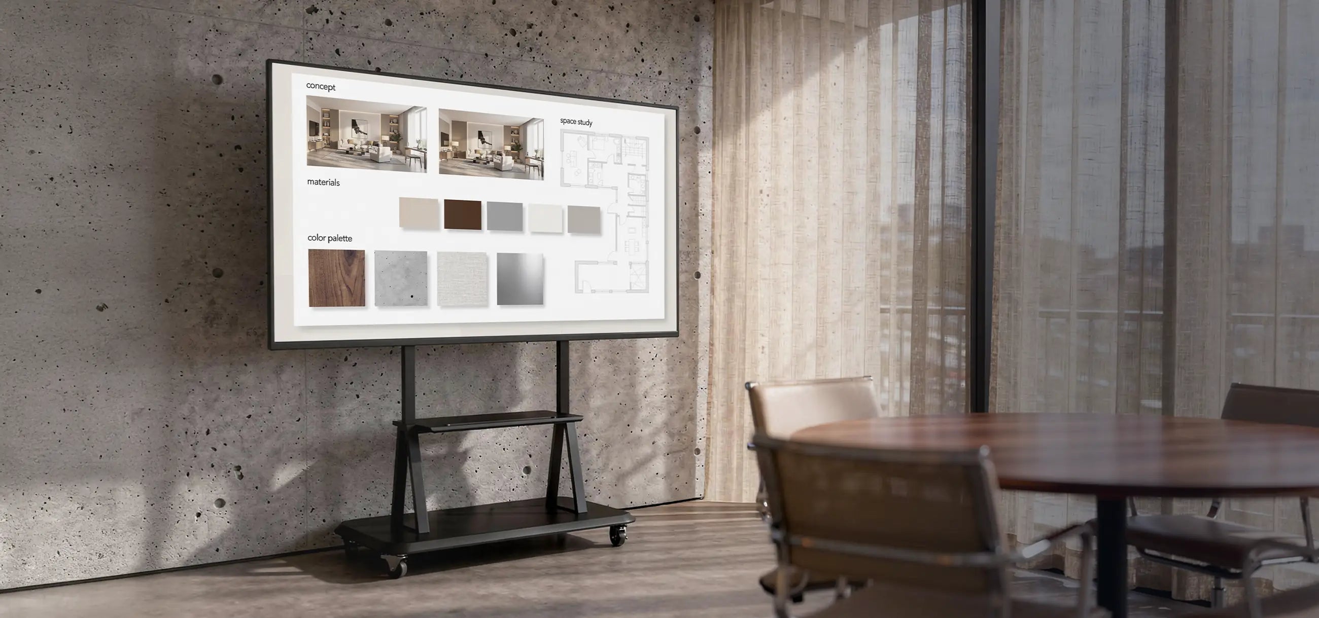 The image shows a modern meeting or creative workspace with a concrete wall and large windows with curtains. At the center stands a mobile presentation display on a celexon Professional height adjustable display trolley Adjust-55120MP, displaying a concept board with interior visualizations, material samples, and color palettes. The scene conveys a professional environment for architecture, design, or project meetings.